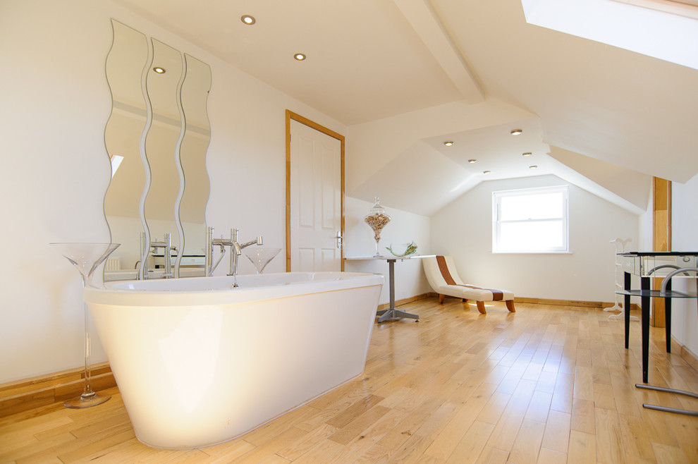 Foto på ett stort funkis badrum, med ett fristående badkar, vita väggar och ljust trägolv