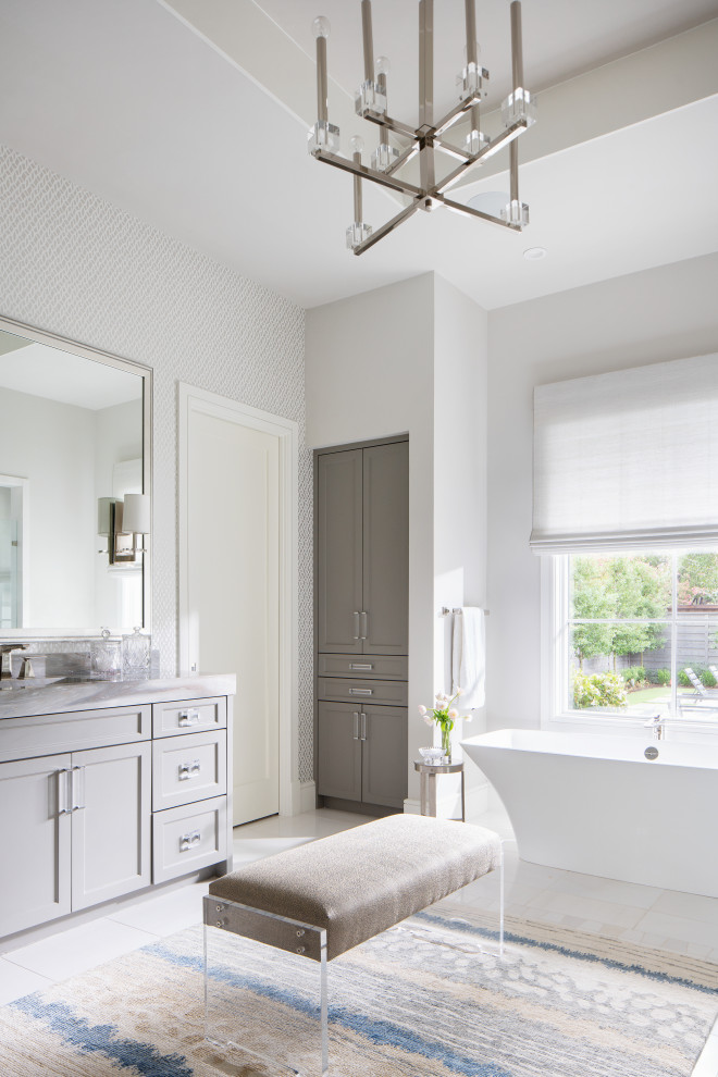 Diseño de cuarto de baño principal contemporáneo con armarios estilo shaker, puertas de armario grises, bañera exenta, paredes blancas y encimeras grises