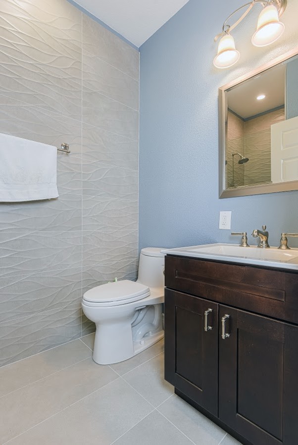 Design ideas for a small contemporary shower room bathroom in Los Angeles with shaker cabinets, dark wood cabinets, a one-piece toilet, blue walls, porcelain flooring, an integrated sink, beige floors, an alcove shower, a hinged door, grey tiles, porcelain tiles and engineered stone worktops.