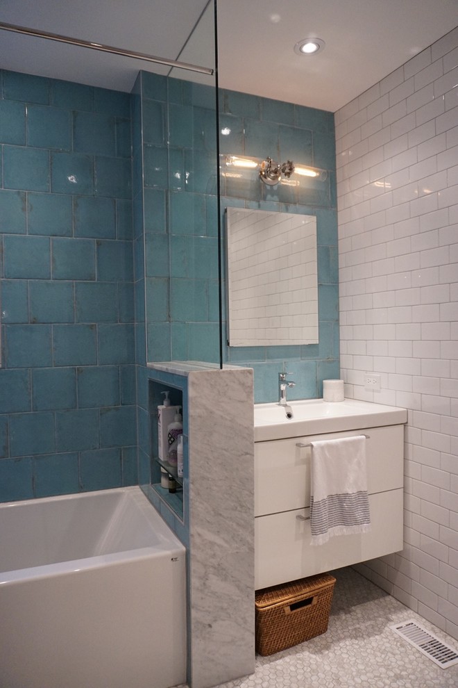 Esempio di una stanza da bagno contemporanea con ante lisce, ante bianche, vasca ad alcova, vasca/doccia, WC sospeso, piastrelle blu, piastrelle in ceramica, pareti bianche, pavimento in marmo, lavabo integrato e top in superficie solida