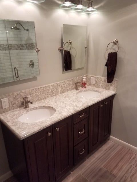 Foto di una stanza da bagno contemporanea con ante con bugna sagomata, ante in legno bruno, top in granito, pareti grigie e lavabo sottopiano