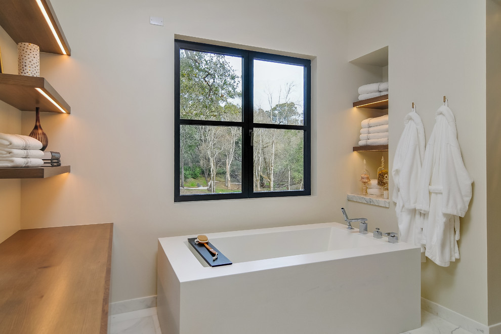 Idee per una stanza da bagno design con vasca freestanding, pareti beige e pavimento bianco