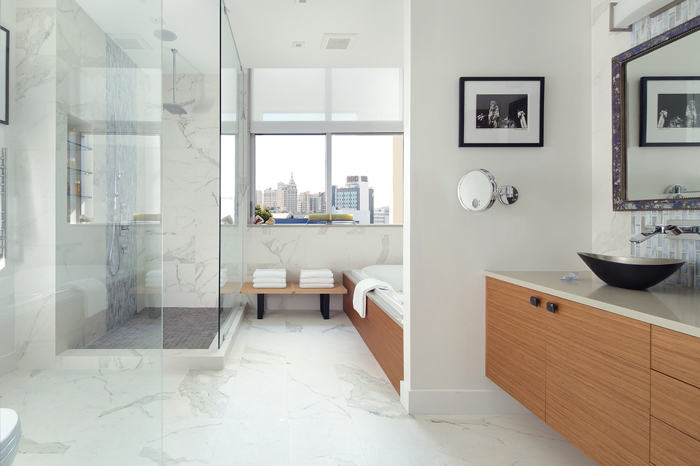 Свежая идея для дизайна: большая главная ванная комната в современном стиле с настольной раковиной, плоскими фасадами, светлыми деревянными фасадами, столешницей из искусственного кварца, накладной ванной, угловым душем, белыми стенами, полом из керамогранита, белой плиткой, унитазом-моноблоком, керамогранитной плиткой, белым полом и душем с распашными дверями - отличное фото интерьера