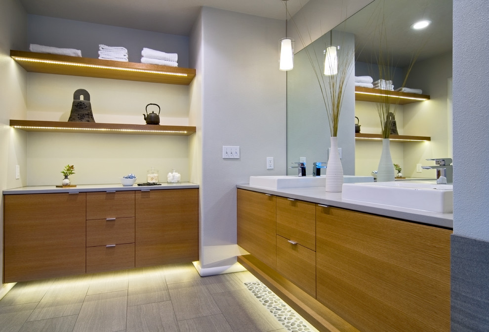 Стильный дизайн: ванная комната в современном стиле с настольной раковиной, плоскими фасадами, фасадами цвета дерева среднего тона и серой плиткой - последний тренд