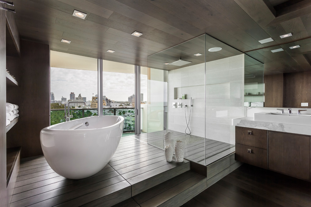 Modernes Badezimmer mit flächenbündigen Schrankfronten, braunen Schränken, freistehender Badewanne, bodengleicher Dusche, brauner Wandfarbe, braunem Holzboden, Aufsatzwaschbecken, grauem Boden und weißer Waschtischplatte in Houston