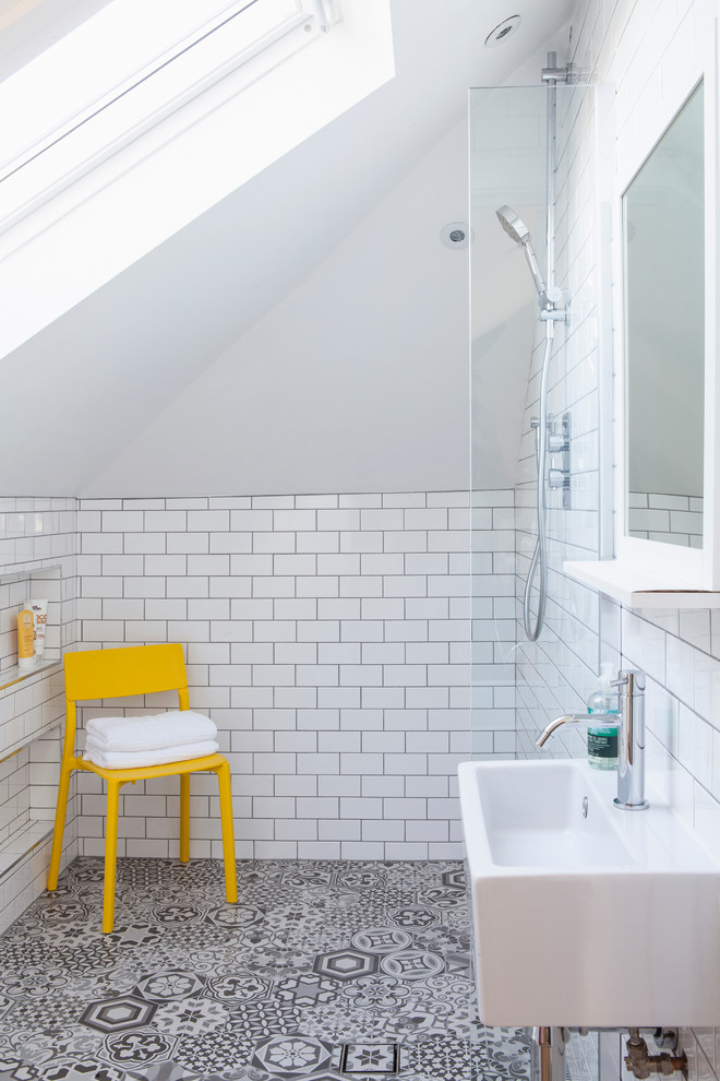 Modern inredning av ett litet en-suite badrum, med en öppen dusch, en vägghängd toalettstol, vit kakel, vita väggar, klinkergolv i keramik, ett väggmonterat handfat, tunnelbanekakel och med dusch som är öppen