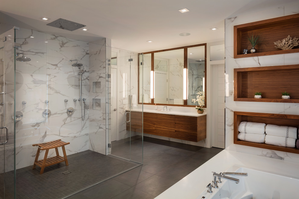 Photo of a contemporary ensuite bathroom in New York with flat-panel cabinets, medium wood cabinets, a submerged bath, white tiles, white walls, a submerged sink, grey floors, a hinged door and a double shower.