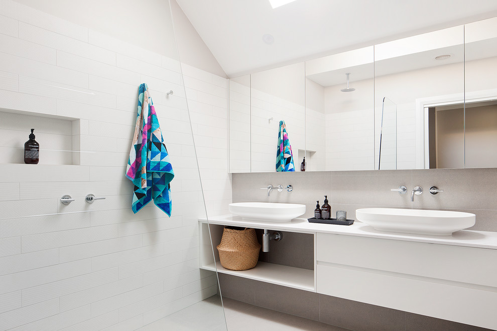 Cette photo montre une salle de bain principale tendance avec une vasque, un placard sans porte, des portes de placard blanches, une douche ouverte, un carrelage blanc, un mur blanc et aucune cabine.