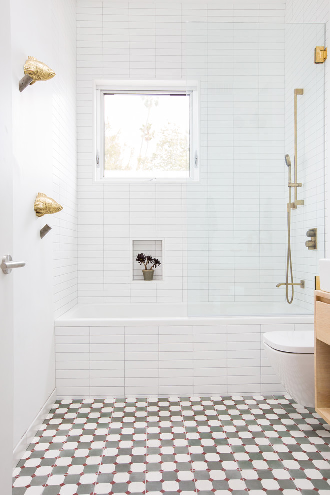 Exempel på ett mellanstort modernt badrum, med släta luckor, skåp i ljust trä, ett badkar i en alkov, en dusch/badkar-kombination, vit kakel, tunnelbanekakel, cementgolv, flerfärgat golv och med dusch som är öppen