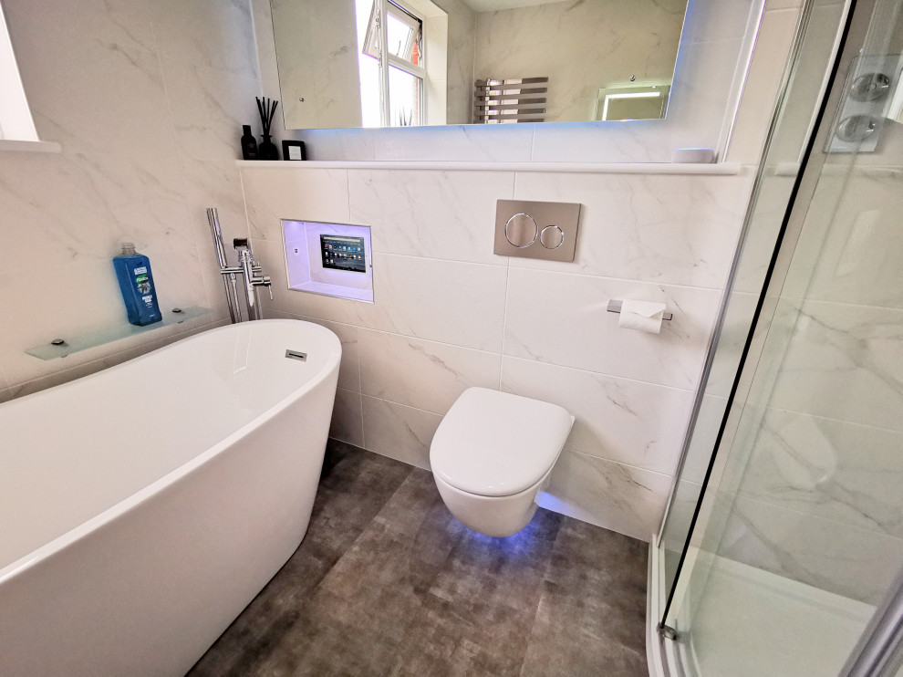 Photo of a medium sized contemporary family bathroom in West Midlands with flat-panel cabinets, white cabinets, a freestanding bath, a corner shower, a wall mounted toilet, black and white tiles, marble tiles, white walls, vinyl flooring, a wall-mounted sink, grey floors, a sliding door, white worktops, a wall niche, a single sink and a floating vanity unit.