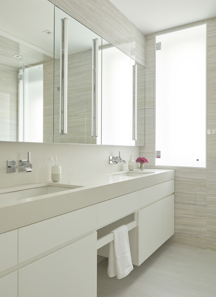 Modernes Badezimmer mit flächenbündigen Schrankfronten, weißen Schränken, beigen Fliesen, grauen Fliesen, beiger Wandfarbe, Unterbauwaschbecken, grauem Boden und grauer Waschtischplatte in New York