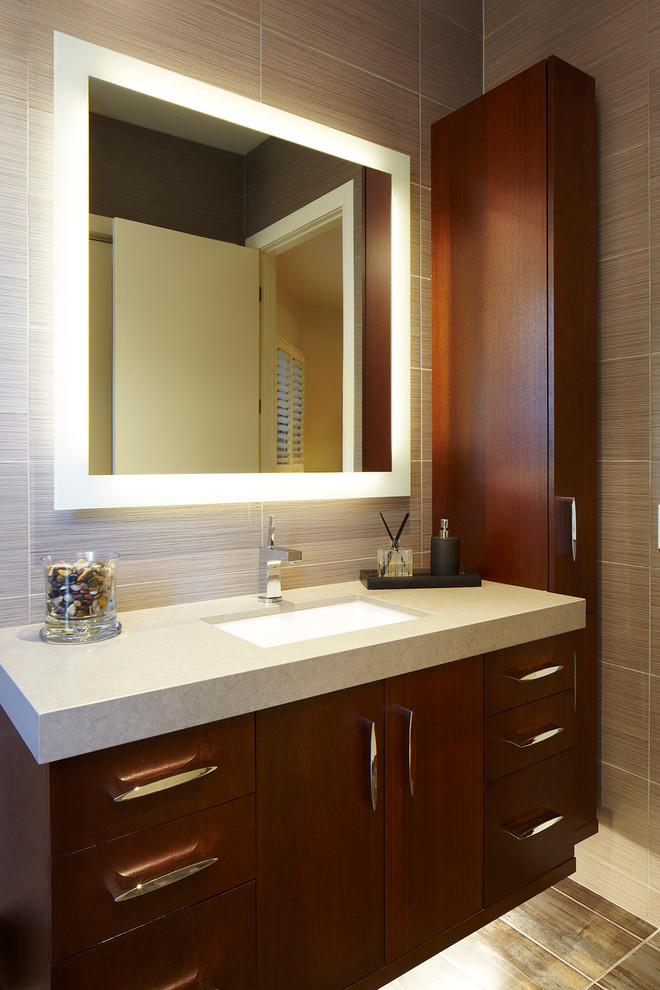 Esempio di una stanza da bagno design con lavabo sottopiano, ante lisce, ante in legno bruno e piastrelle grigie