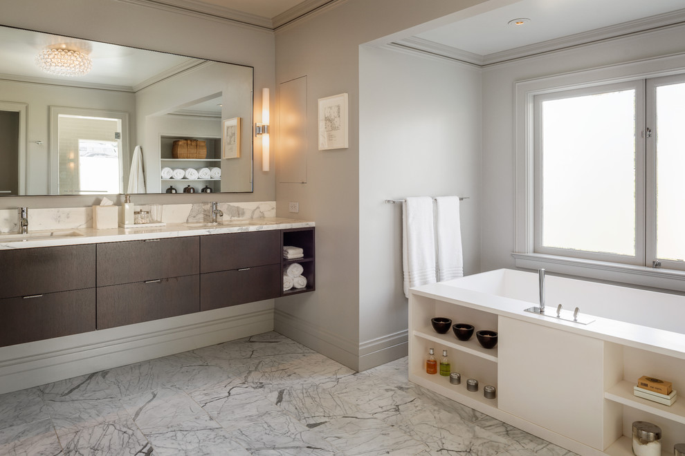 Cette photo montre une salle de bain tendance en bois foncé avec un lavabo encastré, un placard à porte plane et une baignoire indépendante.