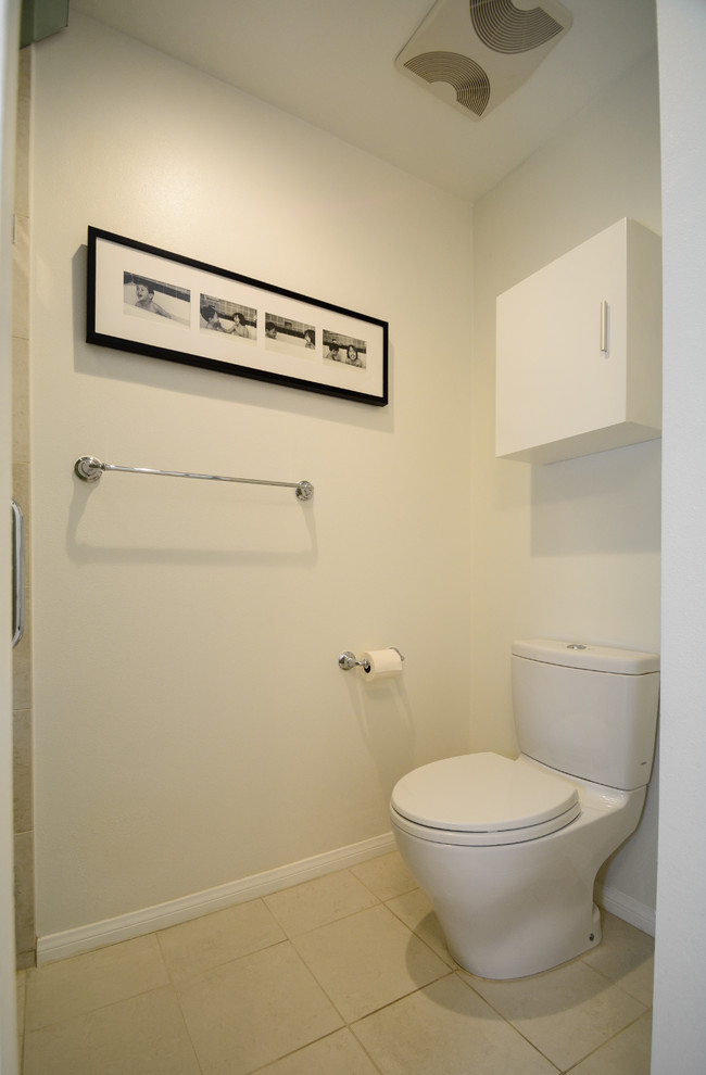 Inspiration pour un WC et toilettes design de taille moyenne avec un placard à porte plane, des portes de placard noires, WC à poser, un carrelage beige, des carreaux de porcelaine et un mur blanc.