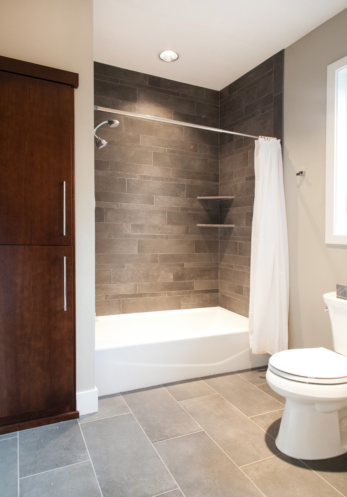 Esempio di una stanza da bagno design con ante lisce, ante in legno bruno, vasca/doccia, WC a due pezzi, piastrelle grigie e piastrelle in ceramica