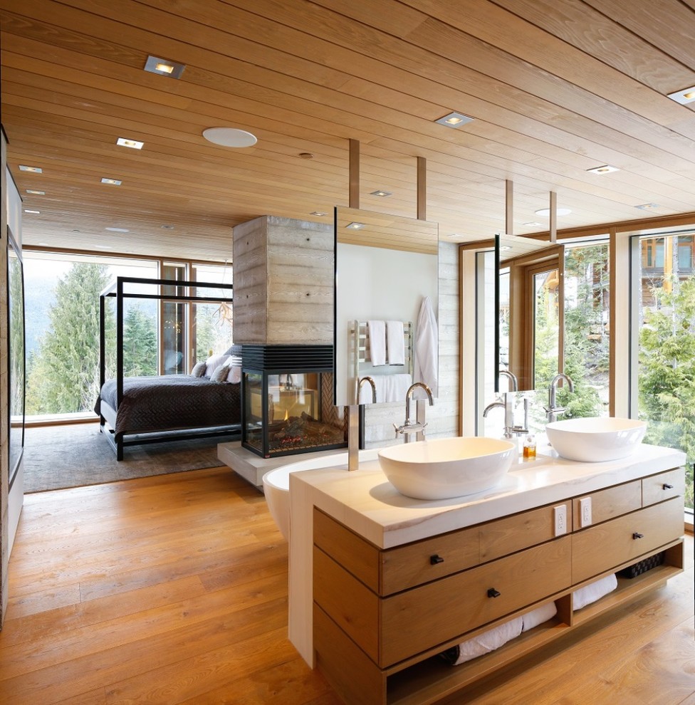Exemple d'une salle de bain principale tendance en bois brun avec un placard à porte plane, une baignoire indépendante, un sol en bois brun, une vasque, un sol marron et un plan de toilette blanc.
