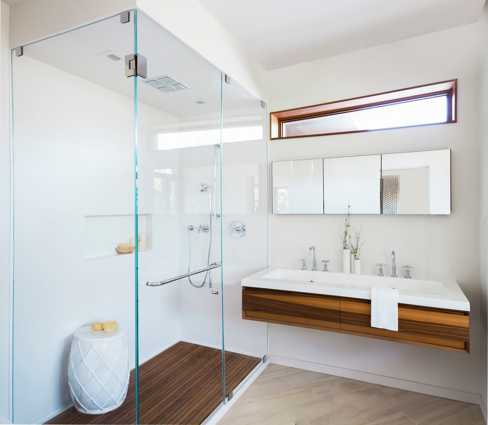 На фото: ванная комната в современном стиле с плоскими фасадами, фасадами цвета дерева среднего тона, угловым душем, белыми стенами, душевой кабиной и монолитной раковиной