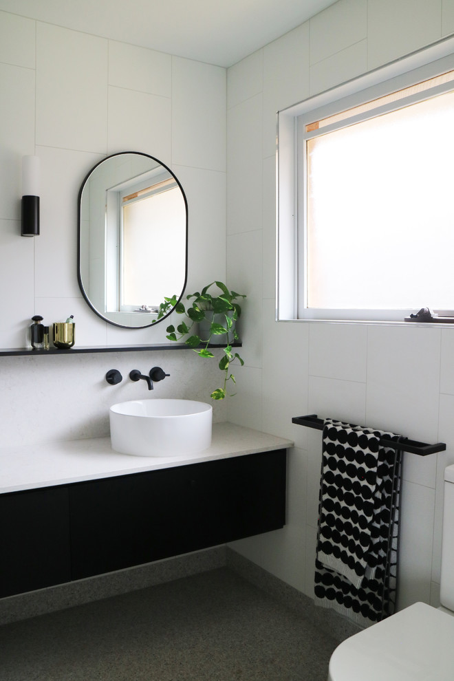 Großes Modernes Badezimmer mit flächenbündigen Schrankfronten, schwarzen Schränken, weißen Fliesen, weißer Wandfarbe, Aufsatzwaschbecken, grauem Boden, weißer Waschtischplatte, offener Dusche, Keramikfliesen, Kiesel-Bodenfliesen und Quarzwerkstein-Waschtisch in Melbourne