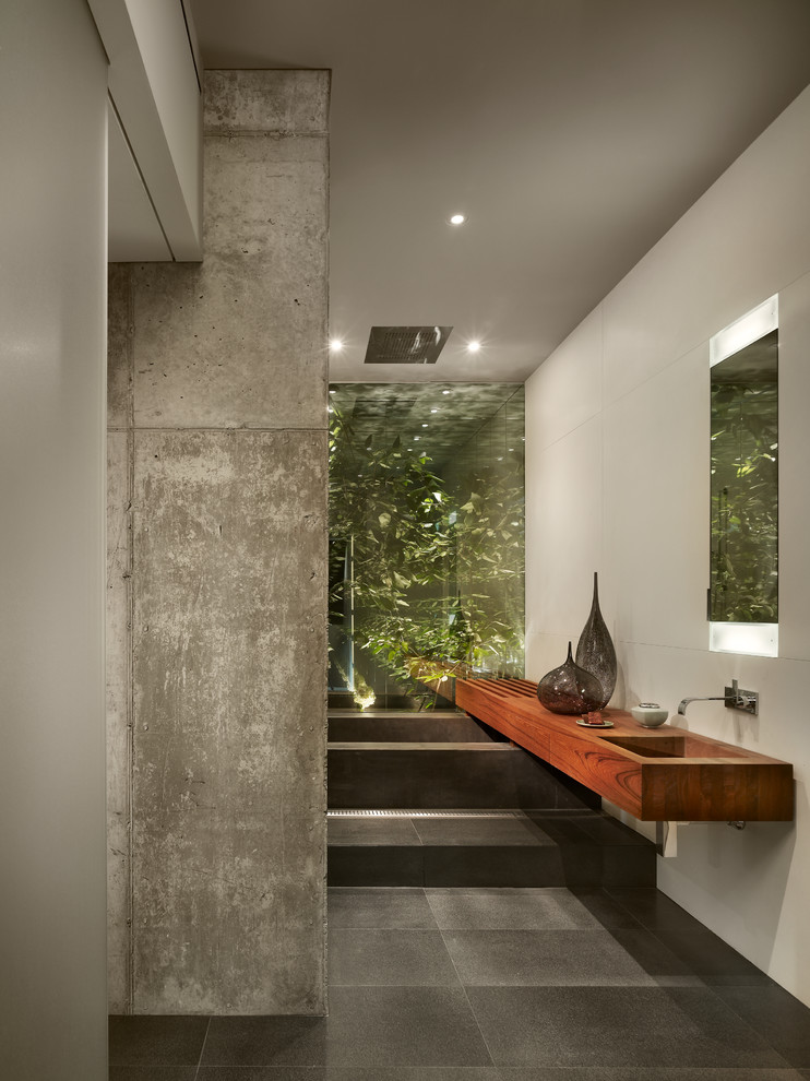 Foto de cuarto de baño actual con lavabo integrado, encimera de madera, paredes blancas y espejo con luz