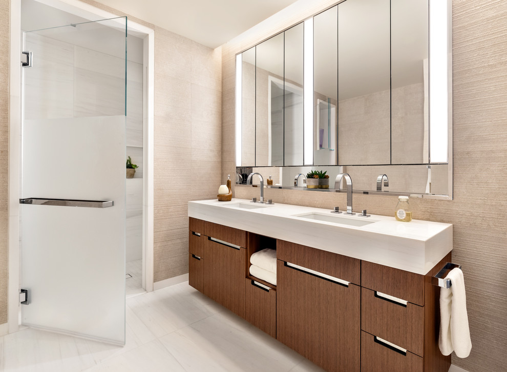 This is an example of a contemporary bathroom in New York with flat-panel cabinets, medium wood cabinets, an alcove shower, beige walls, a submerged sink, white floors, a hinged door and white worktops.