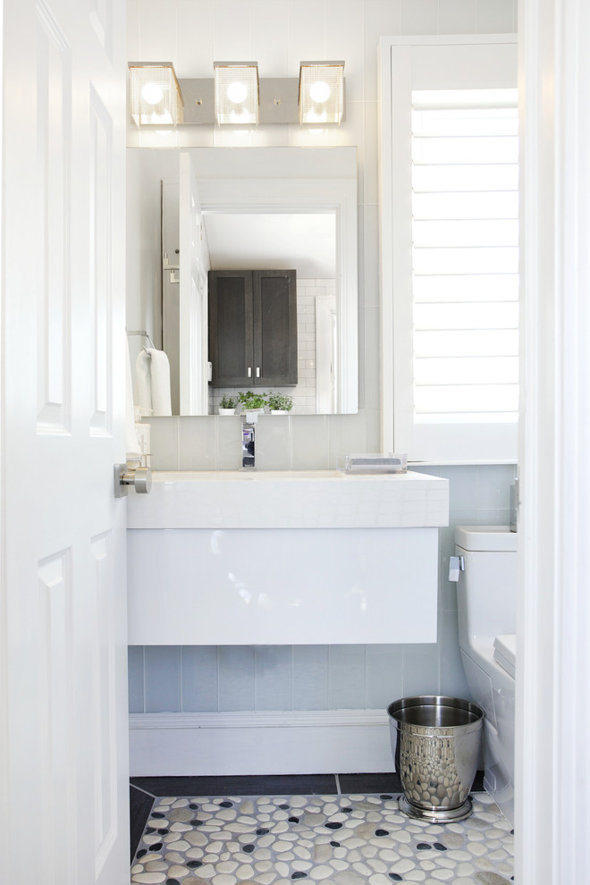 Inspiration för små moderna badrum med dusch, med ett väggmonterat handfat, släta luckor, vita skåp, bänkskiva i akrylsten, en toalettstol med hel cisternkåpa, kakel i småsten, vita väggar och klinkergolv i småsten