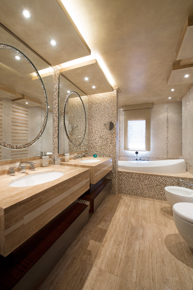 Cette photo montre une salle de bain tendance avec un lavabo encastré, une baignoire posée, un bidet, un carrelage beige, mosaïque et un mur beige.