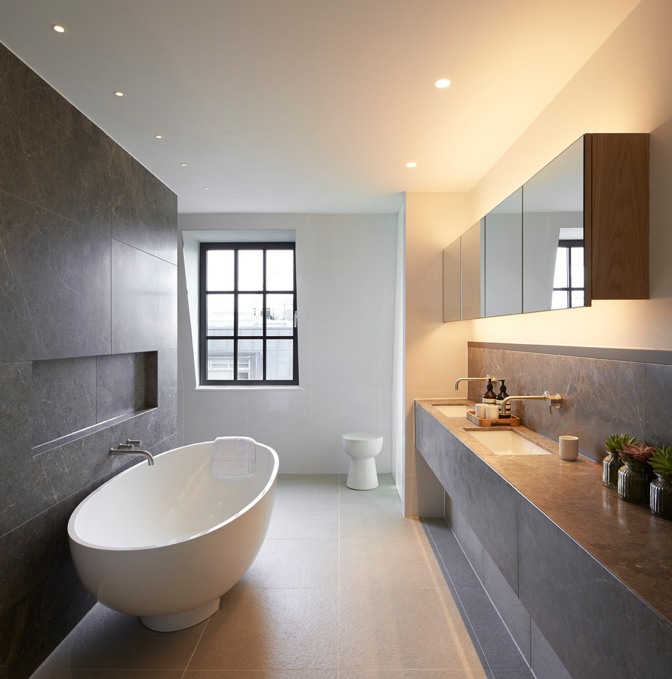 Modern inredning av ett badrum, med släta luckor, ett fristående badkar, vita väggar och ett undermonterad handfat