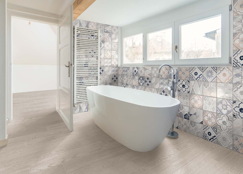 Idée de décoration pour une grande salle de bain principale design avec une baignoire indépendante, un carrelage multicolore, des carreaux de porcelaine, un mur multicolore, un sol en carrelage de porcelaine et un sol gris.
