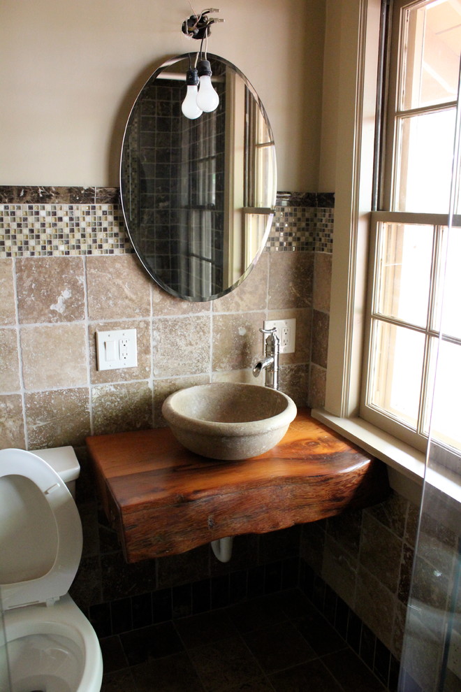 Foto de cuarto de baño principal contemporáneo de tamaño medio con lavabo sobreencimera, encimera de madera, sanitario de una pieza, baldosas y/o azulejos de piedra y paredes beige