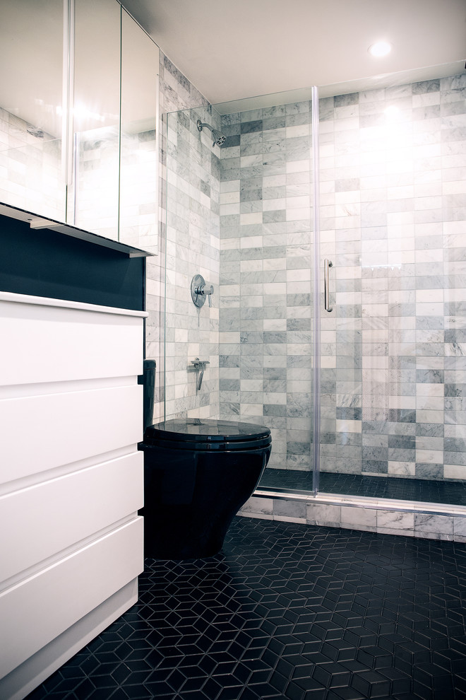 Corner shower - small contemporary master gray tile and marble tile ceramic tile and black floor corner shower idea in San Francisco with flat-panel cabinets, white cabinets, a one-piece toilet, black walls, an integrated sink, a hinged shower door and white countertops