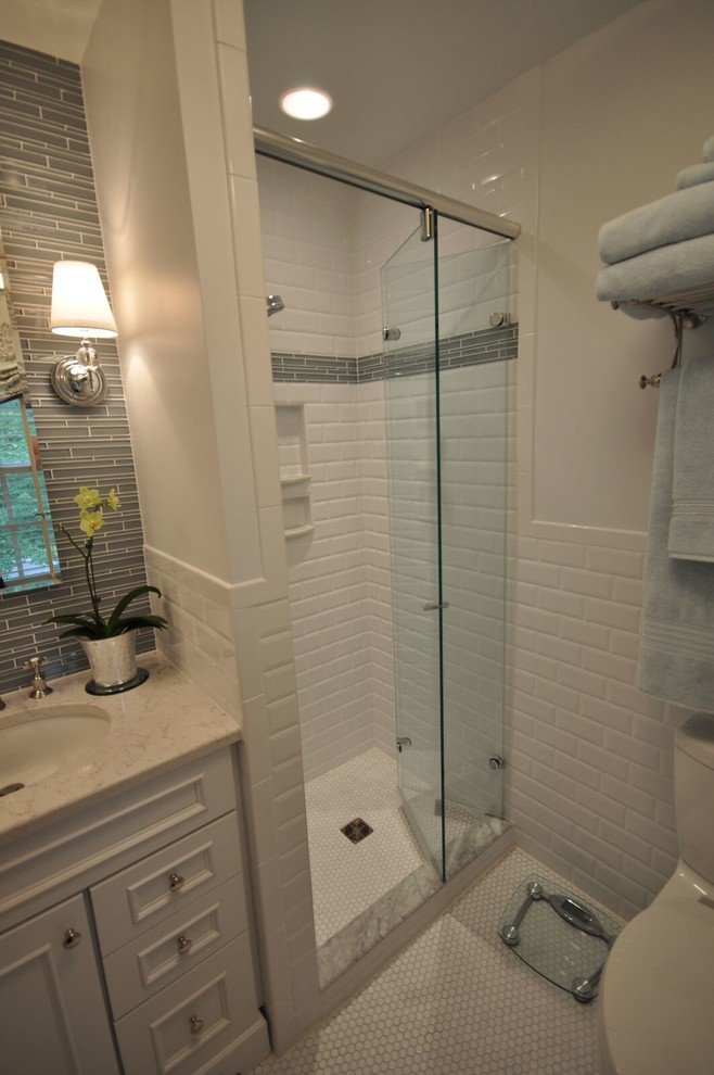 Inredning av ett klassiskt mellanstort badrum med dusch, med luckor med infälld panel, vita skåp, en dusch i en alkov, en toalettstol med separat cisternkåpa, grå kakel, vit kakel, tunnelbanekakel, vita väggar, klinkergolv i keramik, ett undermonterad handfat och bänkskiva i kvarts