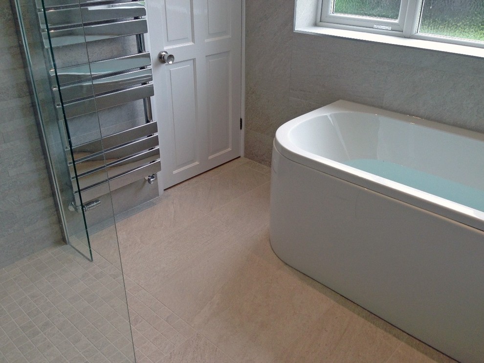 This is an example of a medium sized contemporary family bathroom in Berkshire with flat-panel cabinets, laminate worktops, a built-in bath, a walk-in shower, a one-piece toilet, grey tiles, porcelain tiles, grey walls and porcelain flooring.
