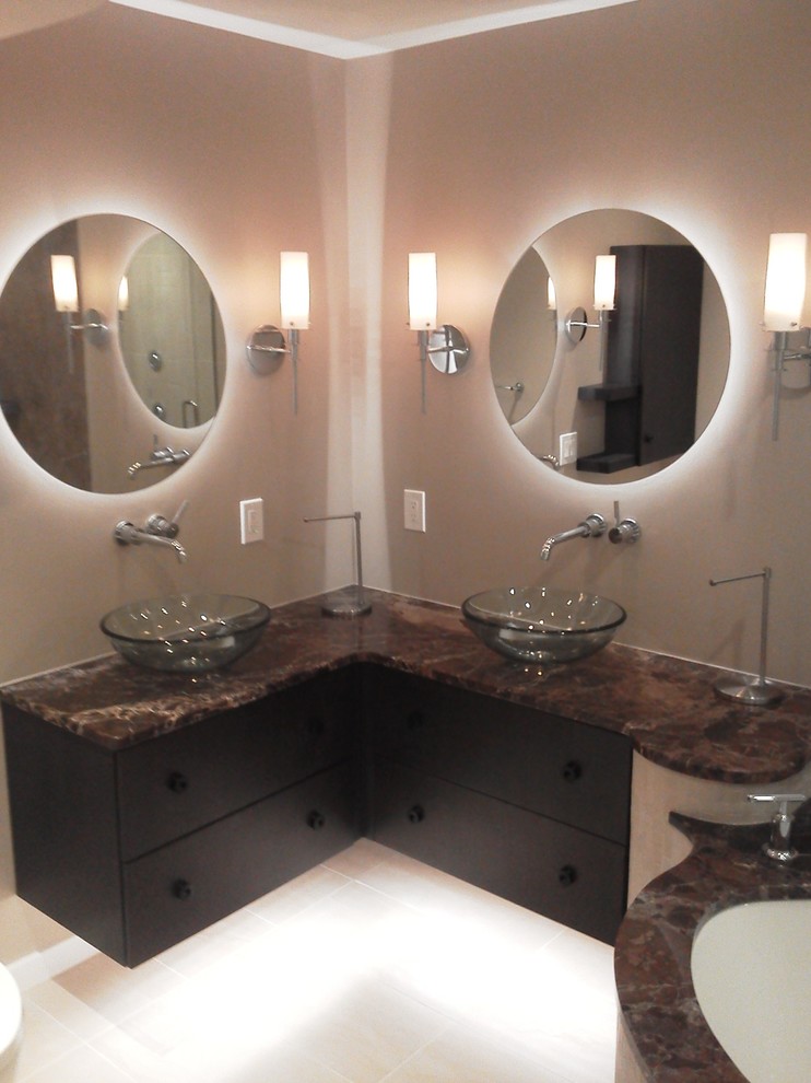 Elegant bathroom photo in New York with a vessel sink, flat-panel cabinets, black cabinets, marble countertops and an undermount tub