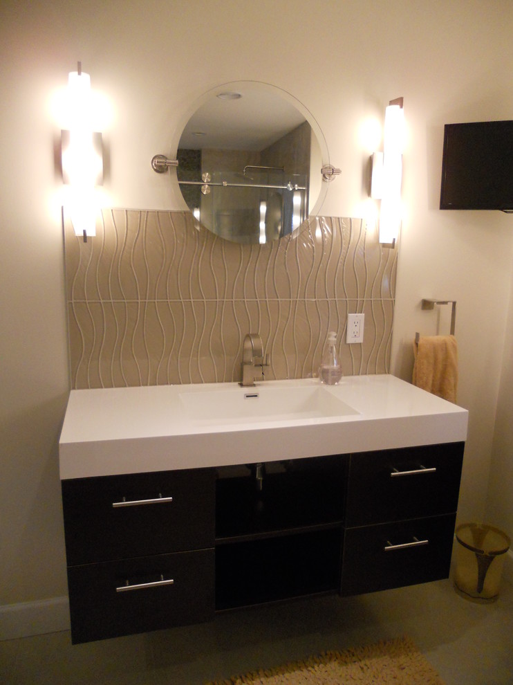 Photo of a medium sized contemporary ensuite bathroom in New York with an integrated sink, flat-panel cabinets, dark wood cabinets, granite worktops, a freestanding bath, a corner shower, a one-piece toilet, beige tiles, porcelain tiles, beige walls and porcelain flooring.