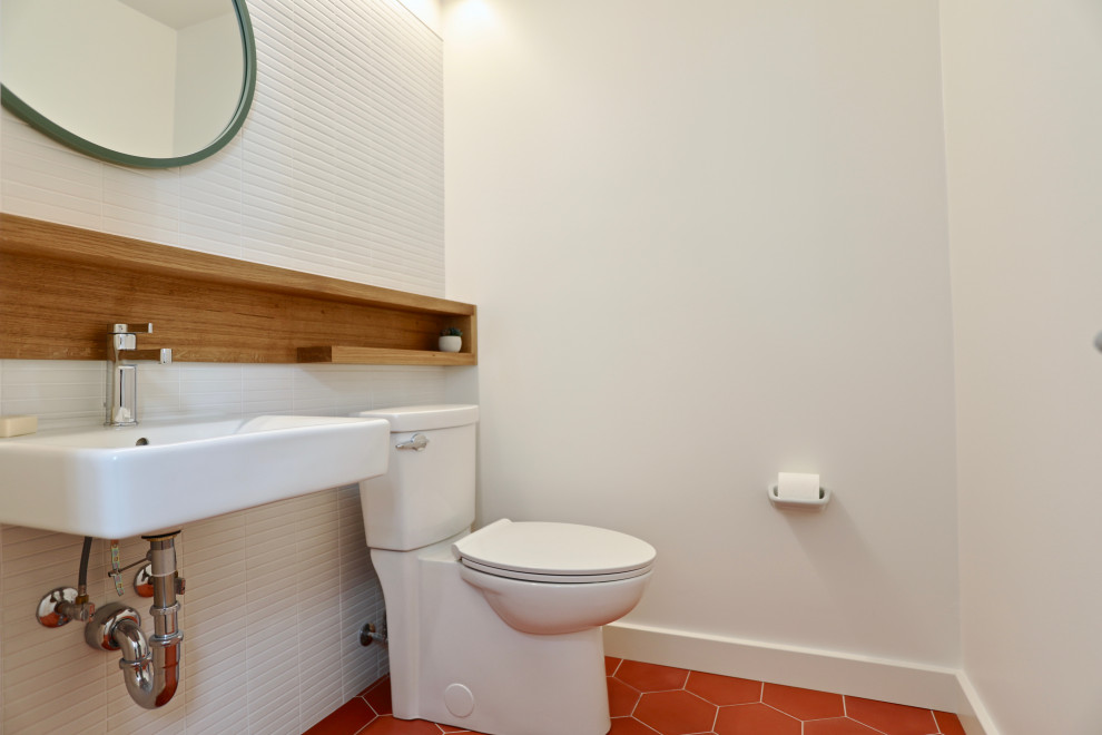 На фото: маленькая ванная комната в современном стиле с ванной в нише, душем над ванной, раздельным унитазом, белой плиткой, керамогранитной плиткой, белыми стенами, бетонным полом, подвесной раковиной, красным полом и шторкой для ванной для на участке и в саду