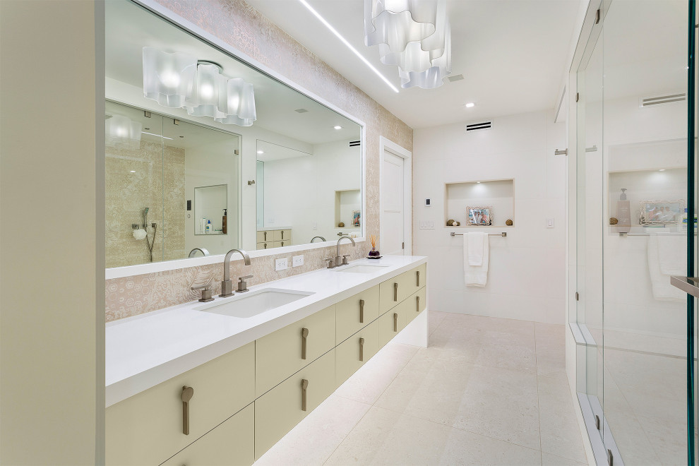 Großes Modernes Badezimmer En Suite mit flächenbündigen Schrankfronten, beigen Schränken, Duschnische, Porzellanfliesen, Porzellan-Bodenfliesen, Unterbauwaschbecken, Mineralwerkstoff-Waschtisch, beigem Boden, Falttür-Duschabtrennung, weißer Waschtischplatte und beigen Fliesen in Miami