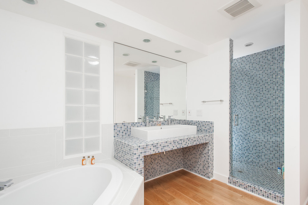 Idéer för att renovera ett mellanstort maritimt en-suite badrum, med ett platsbyggt badkar, en dusch i en alkov, blå kakel, vit kakel, vita väggar, ljust trägolv, ett fristående handfat, kaklad bänkskiva, beiget golv och dusch med gångjärnsdörr