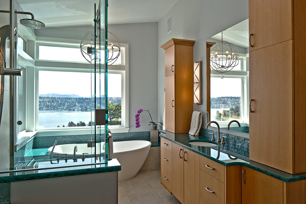 Стильный дизайн: главная ванная комната в морском стиле с врезной раковиной, плоскими фасадами, светлыми деревянными фасадами, столешницей из переработанного стекла, отдельно стоящей ванной, открытым душем и полом из керамогранита - последний тренд