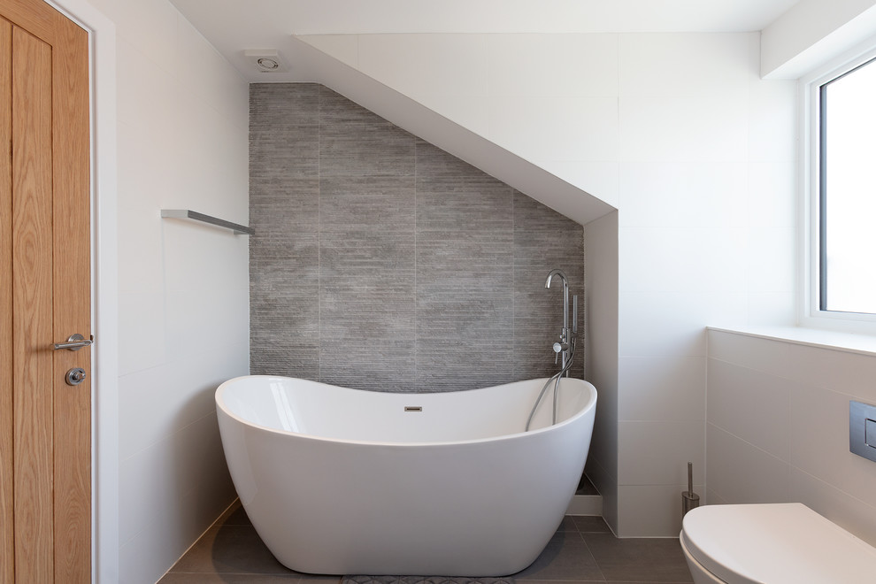 Idee per una stanza da bagno minimalista con vasca freestanding, pareti grigie e pavimento grigio