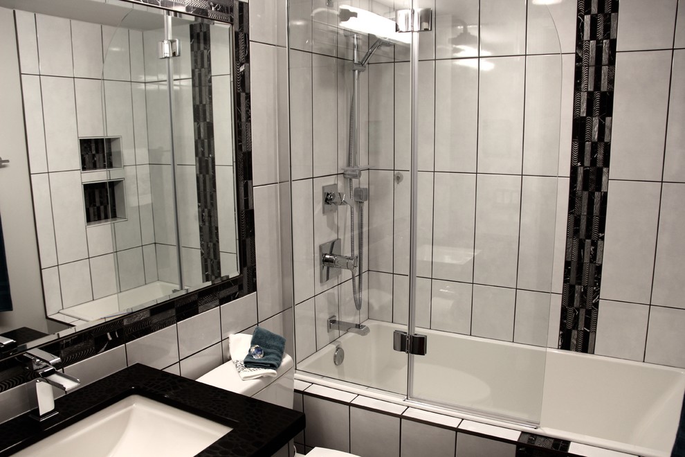 Photo of a small contemporary bathroom in Calgary with flat-panel cabinets, grey cabinets, an alcove bath, a two-piece toilet, white tiles, ceramic tiles, porcelain flooring, a submerged sink and engineered stone worktops.
