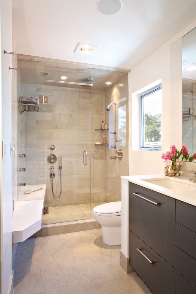 Modernes Badezimmer mit Unterbauwaschbecken, flächenbündigen Schrankfronten, dunklen Holzschränken, beigen Fliesen und Kalkfliesen in Los Angeles