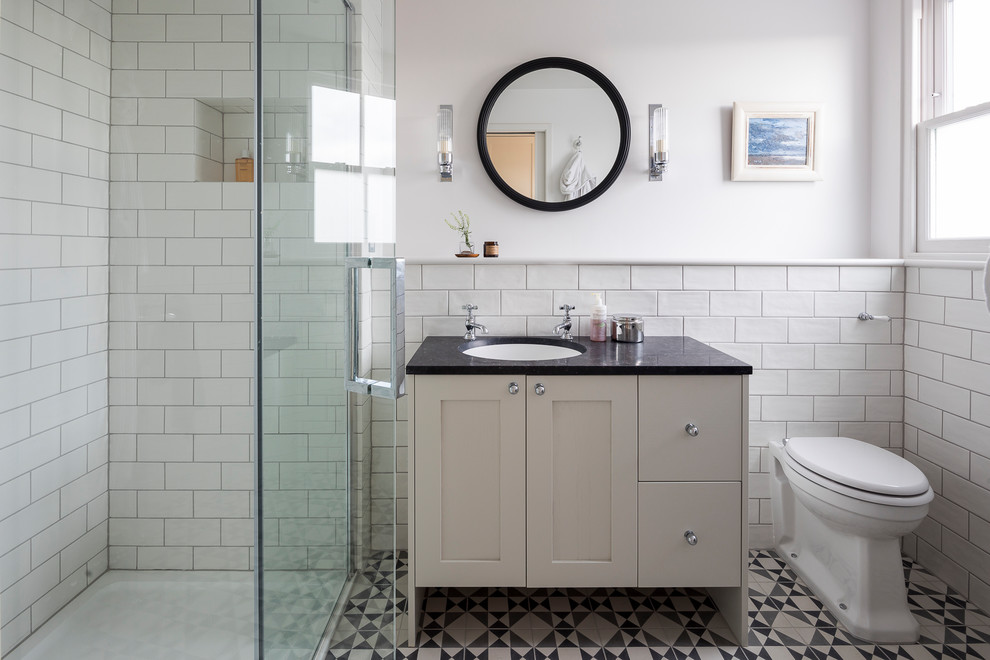 Свежая идея для дизайна: ванная комната в стиле неоклассика (современная классика) с фасадами в стиле шейкер, бежевыми фасадами, душем в нише, унитазом-моноблоком, белой плиткой, плиткой кабанчик, белыми стенами, полом из цементной плитки, душевой кабиной, врезной раковиной, разноцветным полом и душем с распашными дверями - отличное фото интерьера
