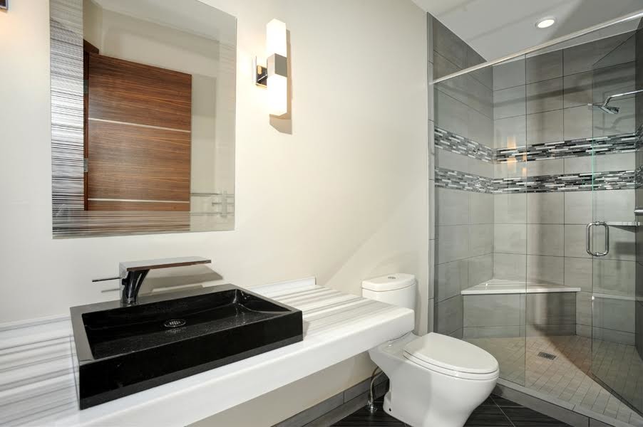 Стильный дизайн: ванная комната среднего размера в современном стиле с душем в нише, унитазом-моноблоком, черной плиткой, черно-белой плиткой, серой плиткой, удлиненной плиткой, белыми стенами, полом из керамогранита, душевой кабиной, настольной раковиной, столешницей из искусственного камня, черным полом и душем с распашными дверями - последний тренд