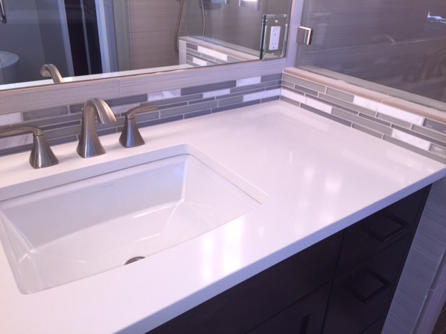 This is an example of a medium sized contemporary ensuite bathroom in Albuquerque with flat-panel cabinets, dark wood cabinets, a freestanding bath, a built-in shower, a one-piece toilet, grey tiles, porcelain tiles, grey walls, porcelain flooring, a submerged sink and quartz worktops.