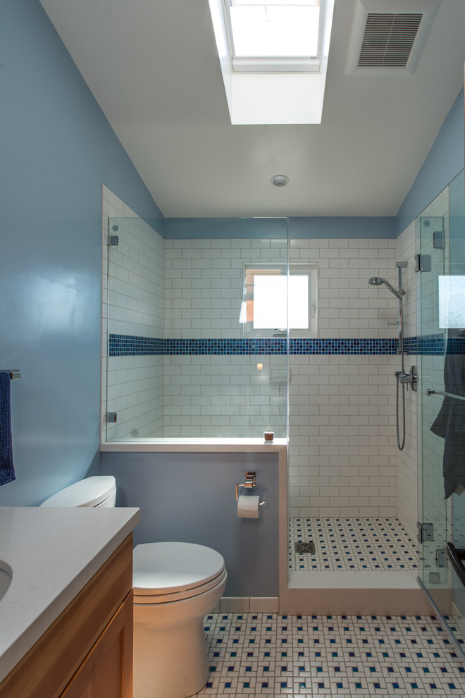Idéer för mellanstora amerikanska grått badrum med dusch, med skåp i shakerstil, skåp i ljust trä, en dusch i en alkov, vit kakel, tunnelbanekakel, grå väggar, klinkergolv i porslin, ett undermonterad handfat, bänkskiva i akrylsten, vitt golv, dusch med gångjärnsdörr och en toalettstol med separat cisternkåpa