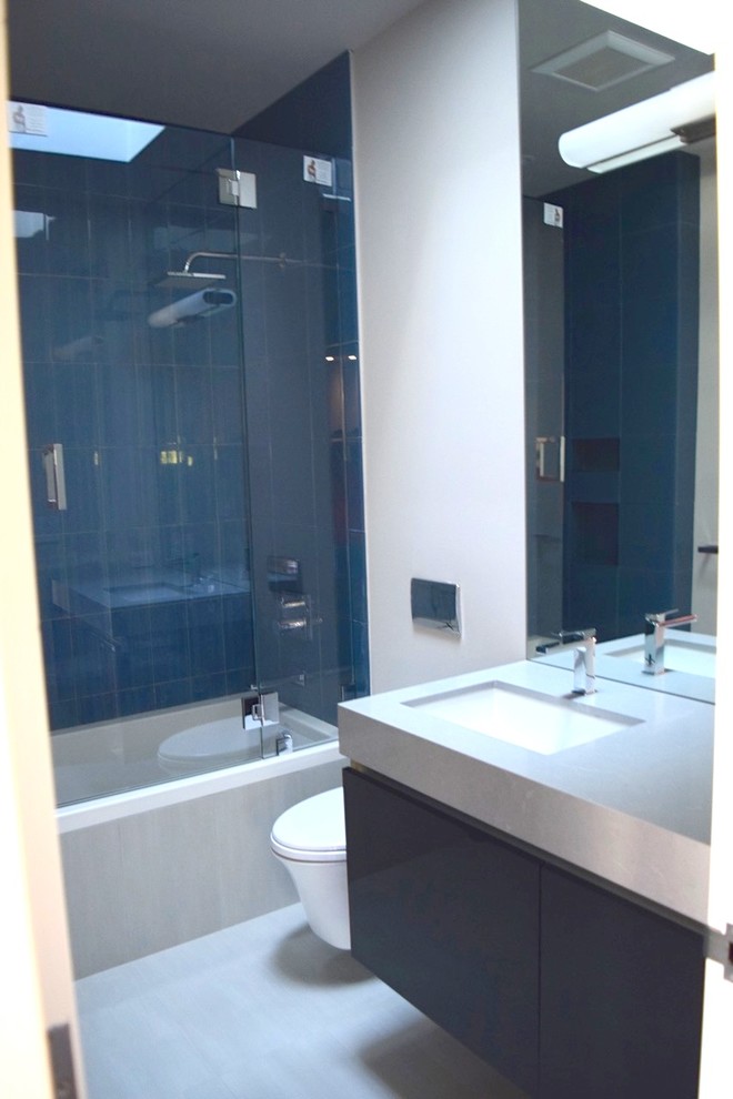 Exempel på ett mellanstort modernt en-suite badrum, med släta luckor, skåp i mörkt trä, ett hörnbadkar, en dusch/badkar-kombination, en toalettstol med hel cisternkåpa, vita väggar, ett undermonterad handfat och bänkskiva i täljsten