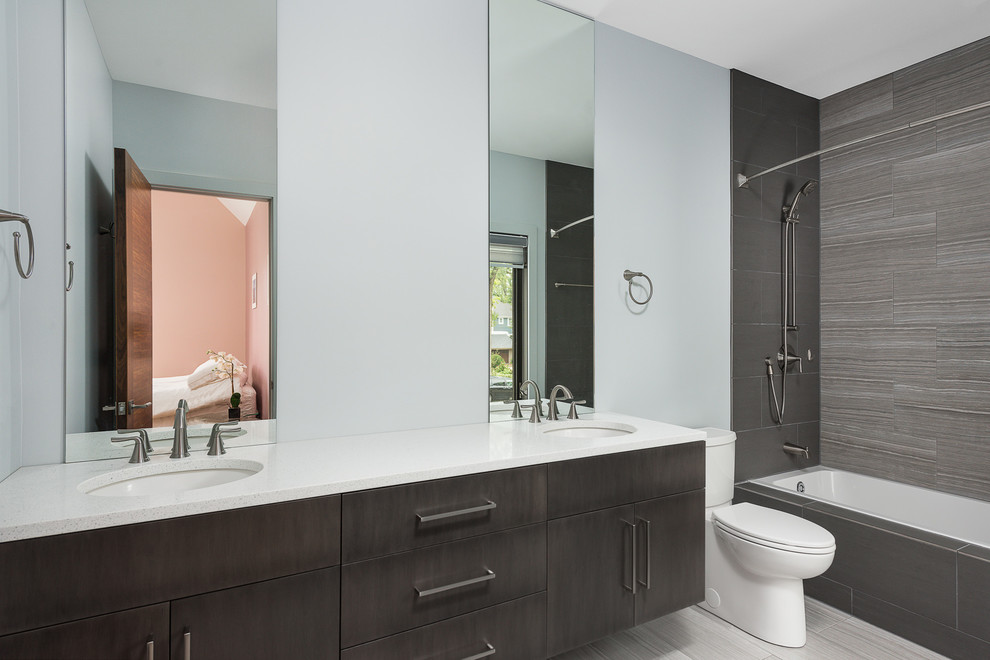 Example of a mid-sized trendy brown tile, gray tile and porcelain tile porcelain tile and gray floor bathroom design in Chicago with flat-panel cabinets, gray cabinets, a two-piece toilet, white walls, an undermount sink, quartz countertops and white countertops