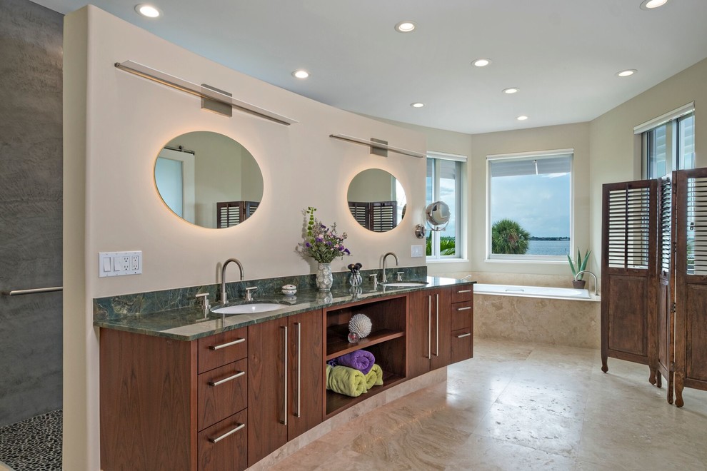 World-inspired ensuite bathroom in Miami with flat-panel cabinets, dark wood cabinets, a built-in bath, beige walls, a submerged sink and beige floors.