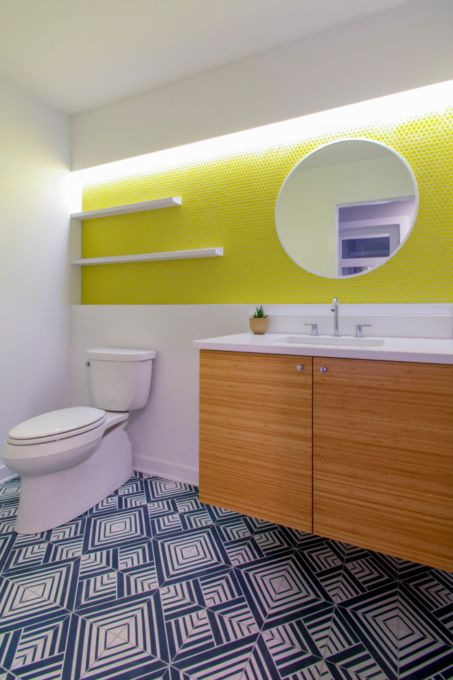 Kleines Modernes Badezimmer mit flächenbündigen Schrankfronten, hellen Holzschränken, Wandtoilette mit Spülkasten, gelben Fliesen, Porzellanfliesen, weißer Wandfarbe, Unterbauwaschbecken, Quarzwerkstein-Waschtisch, blauem Boden, weißer Waschtischplatte und Zementfliesen für Boden in Milwaukee