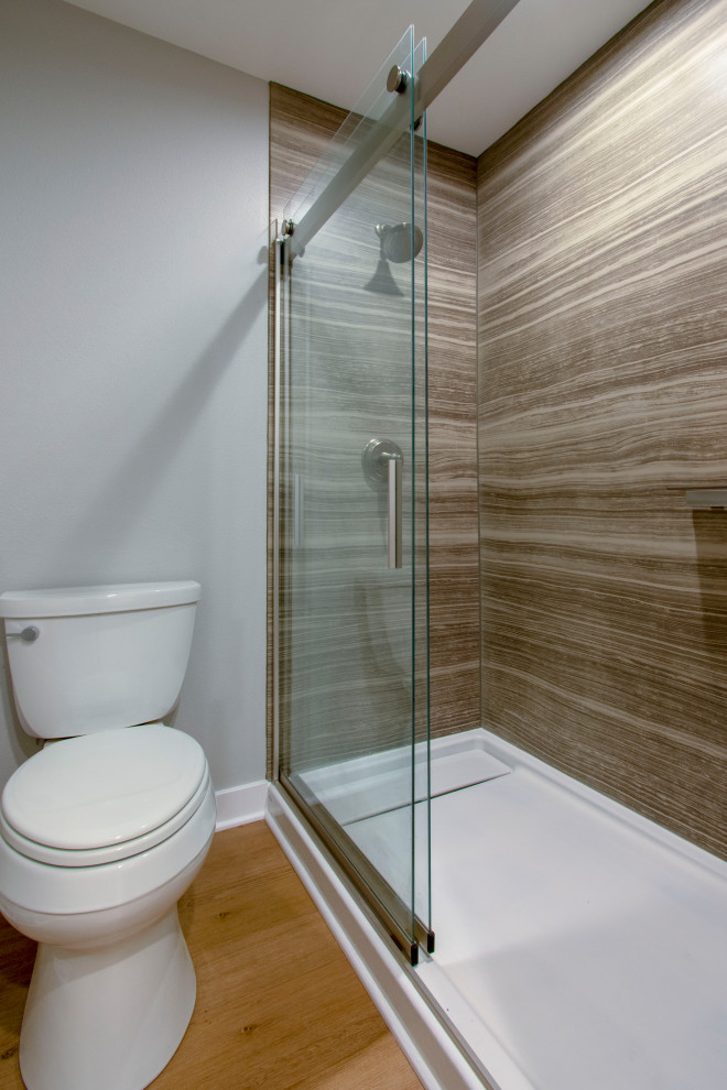 Réalisation d'une grande salle de bain design avec une douche à l'italienne, WC séparés, des dalles de pierre, un mur gris, un sol en vinyl, un plan de toilette en quartz modifié, un sol marron et une cabine de douche à porte coulissante.